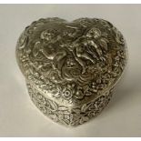 An Edwardian silver love heart shaped trinket box and cover, repousse worked with three cherubs