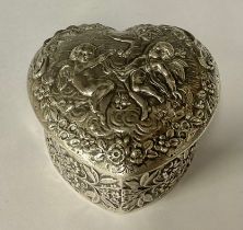 An Edwardian silver love heart shaped trinket box and cover, repousse worked with three cherubs