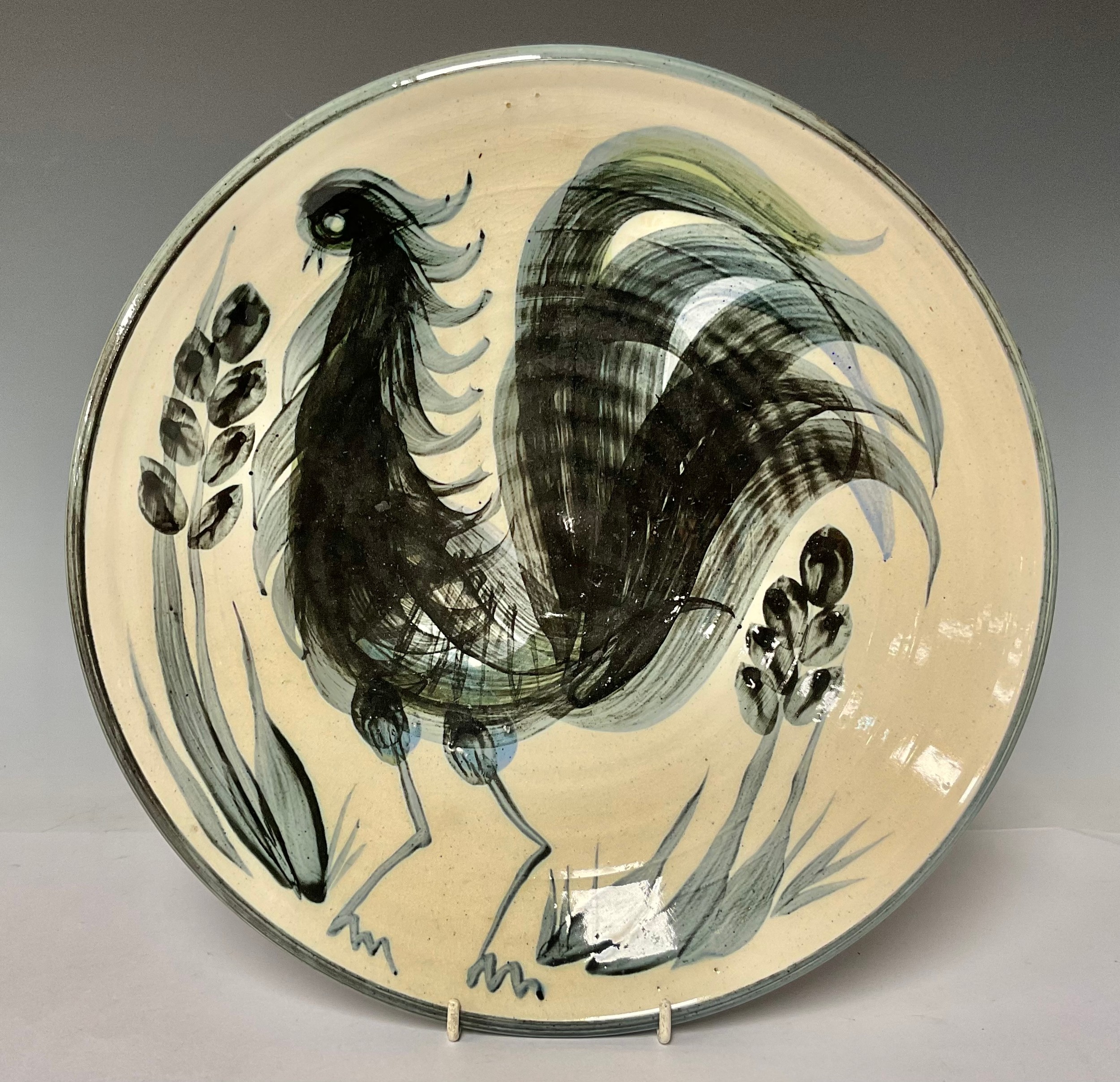 A mid-20th century stoneware circular charger, painted with a stylised rooster in monochrome, 33cm