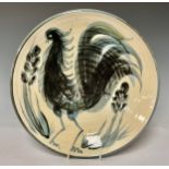 A mid-20th century stoneware circular charger, painted with a stylised rooster in monochrome, 33cm