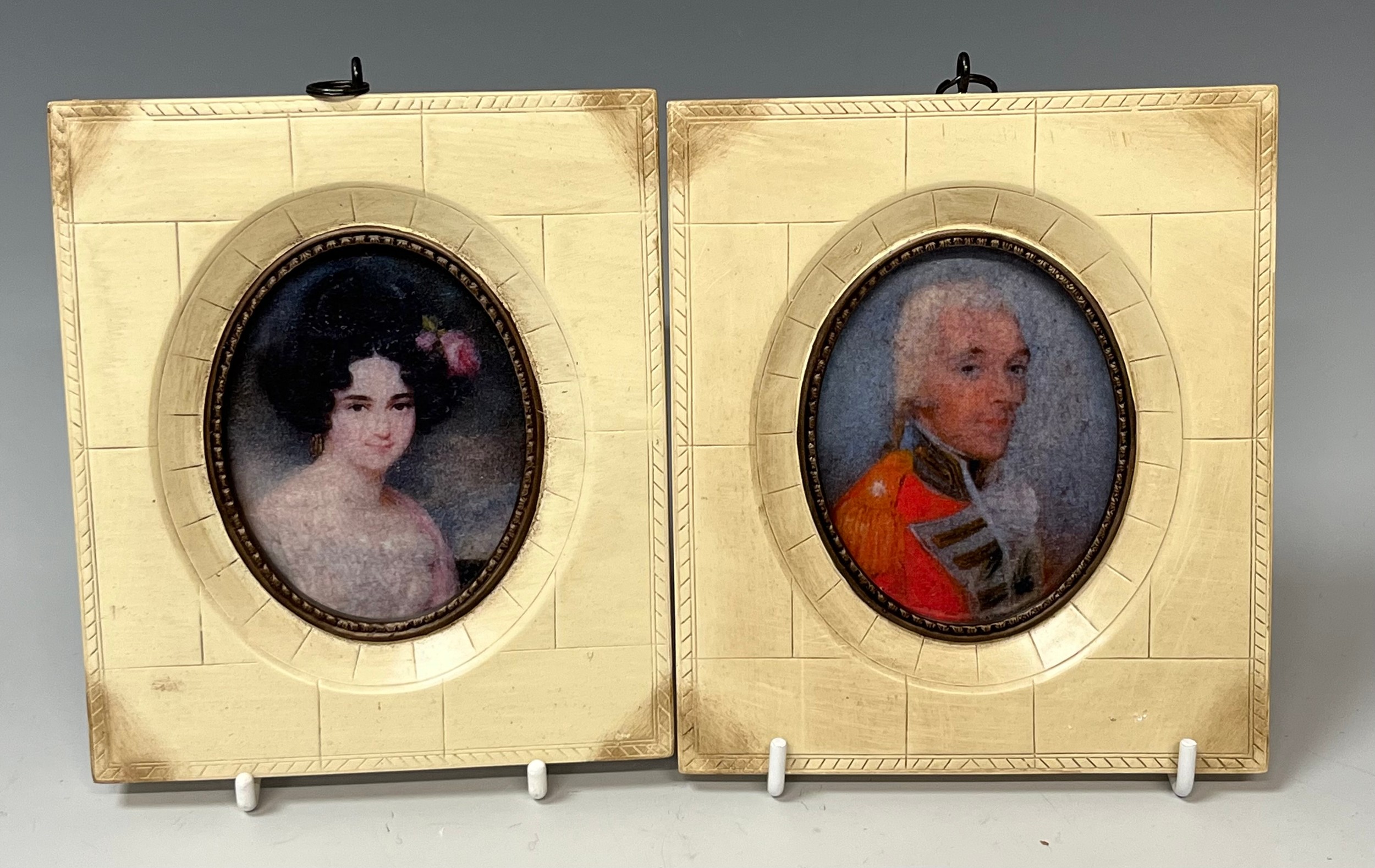 A reproduction pair of white framed oval miniatures, a gentleman and lady, each 13.5cm high, 12cm