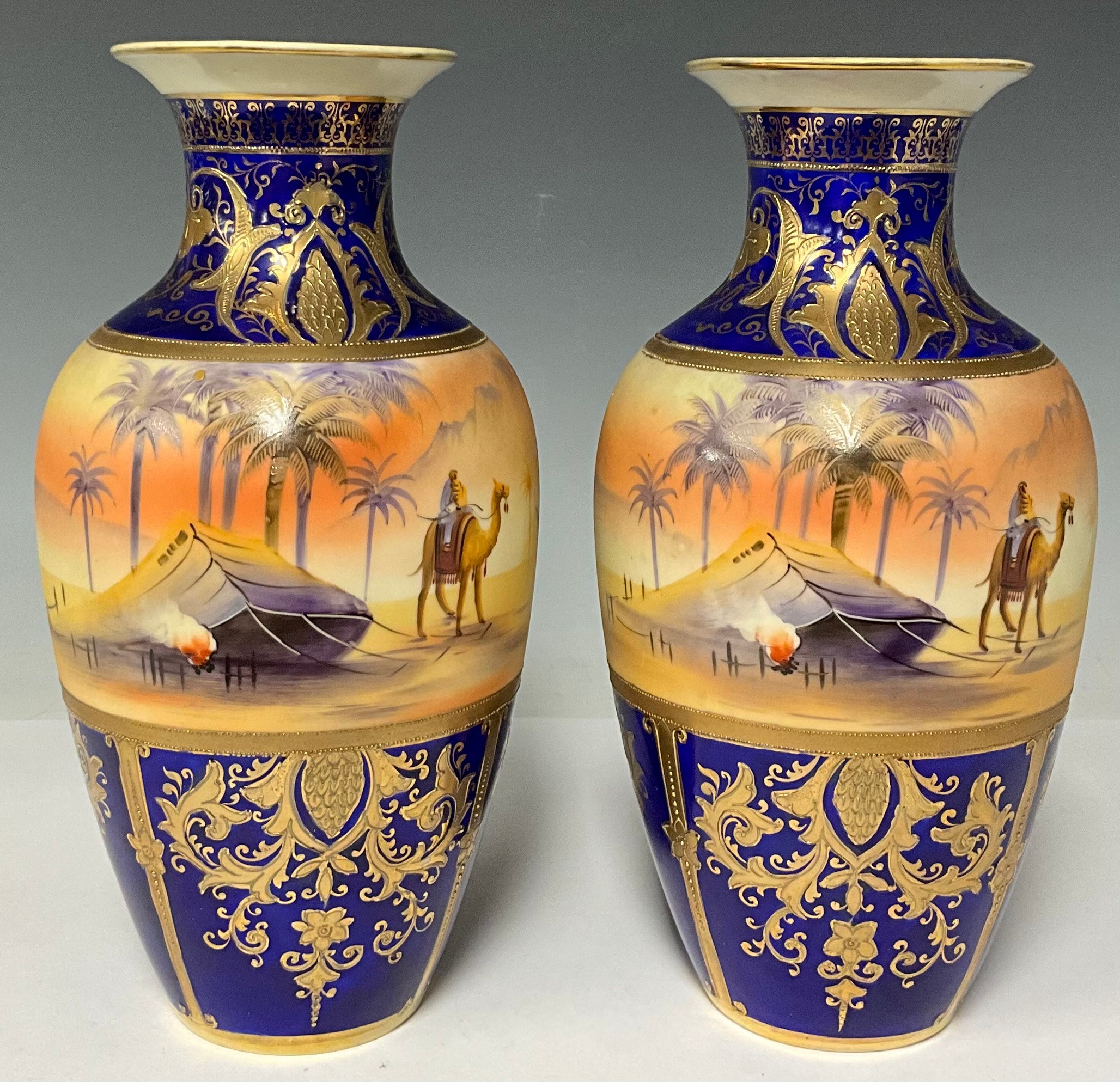 A pair of Noritake baluster vases, printed and painted with desert scenes and tall palm trees, 26cm,