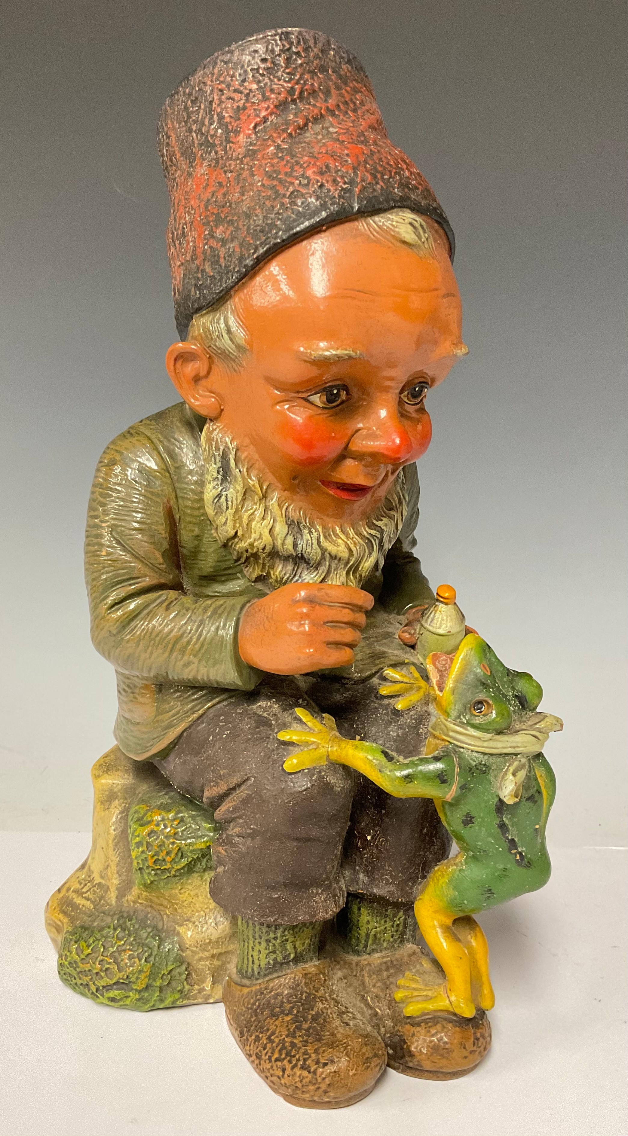 A German Heissner garden gnome model, seated with frog companion, painted in bright colours, 34cm,