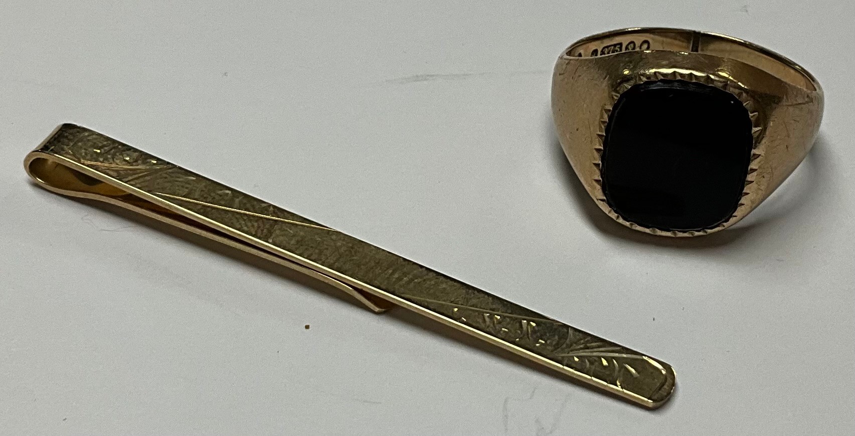 A 9ct gold tie clip, marked 375, 2.2g; a 9ct gold black onyx signet ring, size P, 4.4g (2)