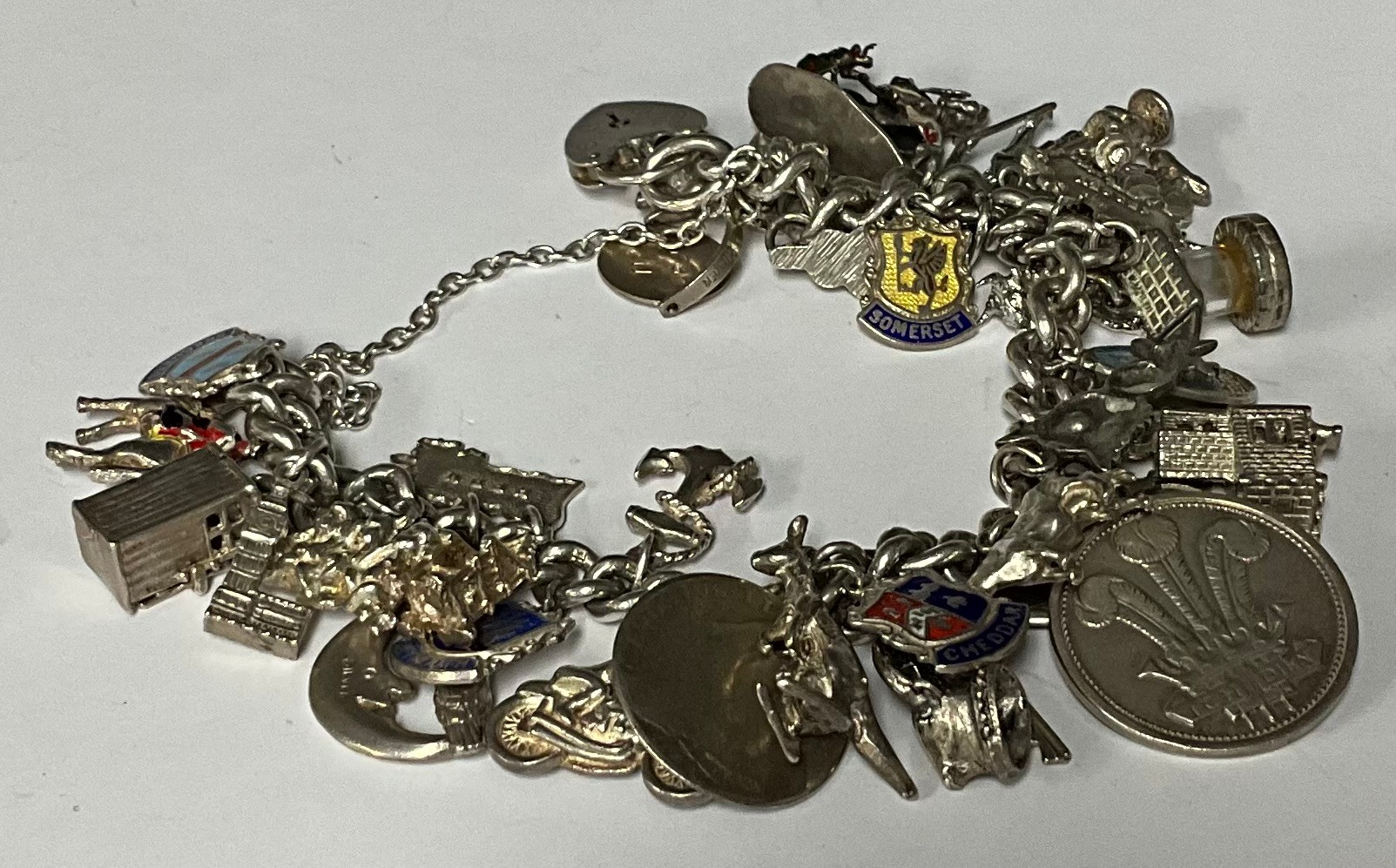 A silver curb link charm bracelet, suspended with a collection of mostly sterling silver charms,