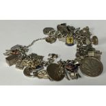 A silver curb link charm bracelet, suspended with a collection of mostly sterling silver charms,