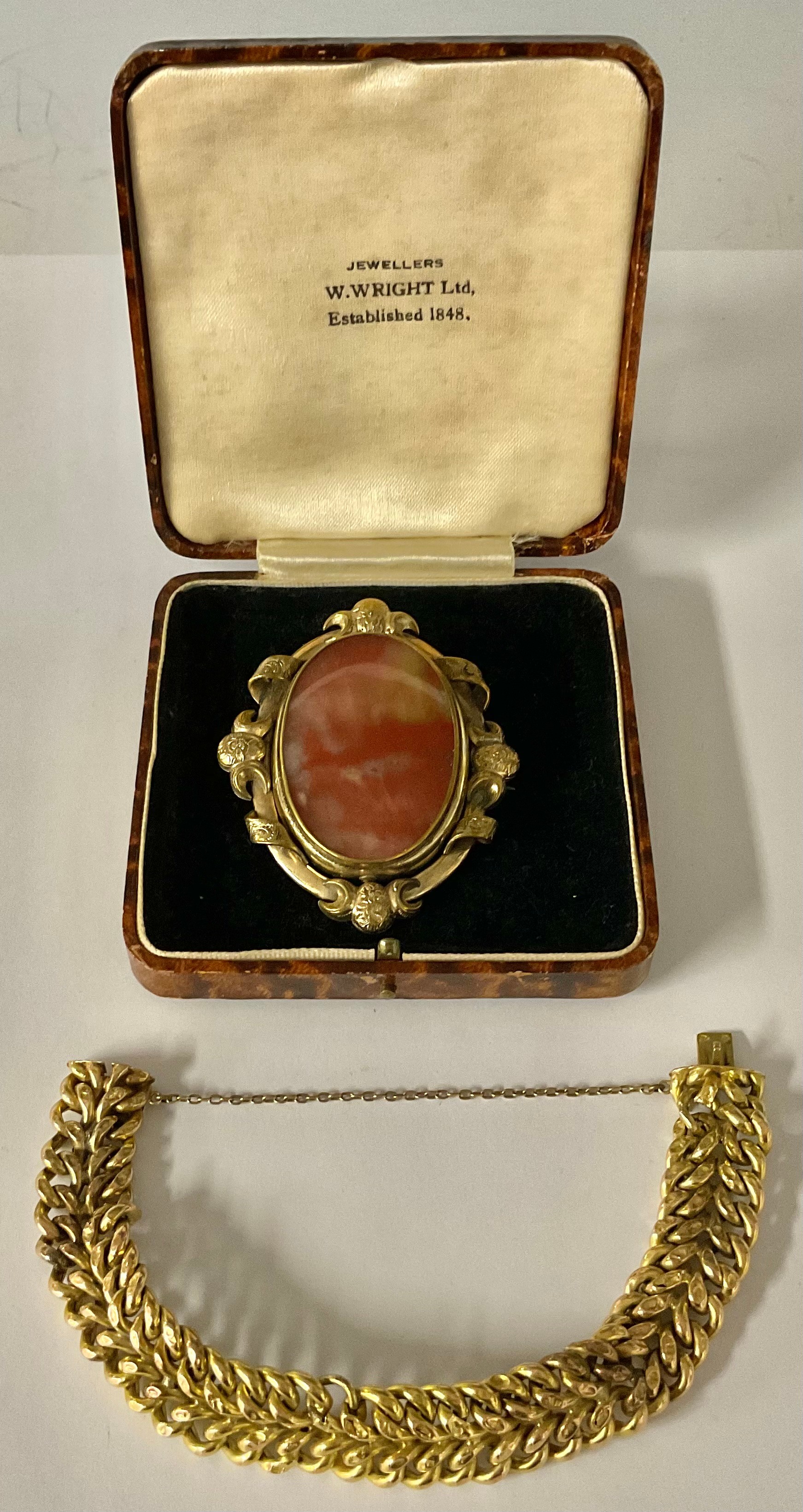 A Victorian gold plated oval brooch/pendant, scroll border, set with a polished red agate oval,