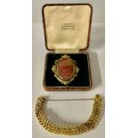 A Victorian gold plated oval brooch/pendant, scroll border, set with a polished red agate oval,