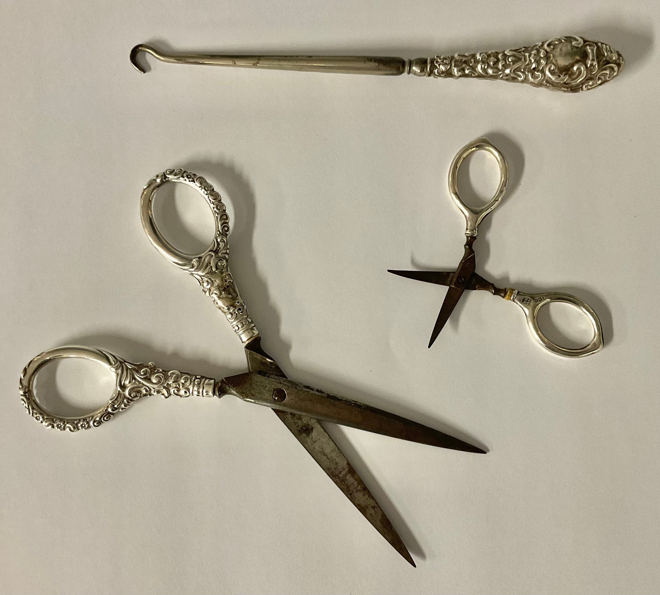 A pair of silver hafted scissors, Birmingham, 1928, 13.6g gross, 7.5cm long; another pair, unmarked,