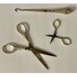 A pair of silver hafted scissors, Birmingham, 1928, 13.6g gross, 7.5cm long; another pair, unmarked,