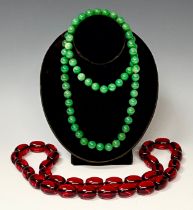 A string of green jade effect beads, approx. 80cm long; a string of faux amber beads, approx. 80cm