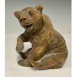 A German Black Forest carved wooden bear, seated, glass eyes, 11.5cm, c.1900