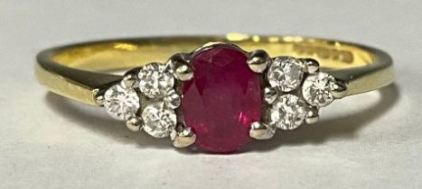 An 18ct gold ring, the central oval cut ruby flanked by three diamonds to either shoulder, size P,