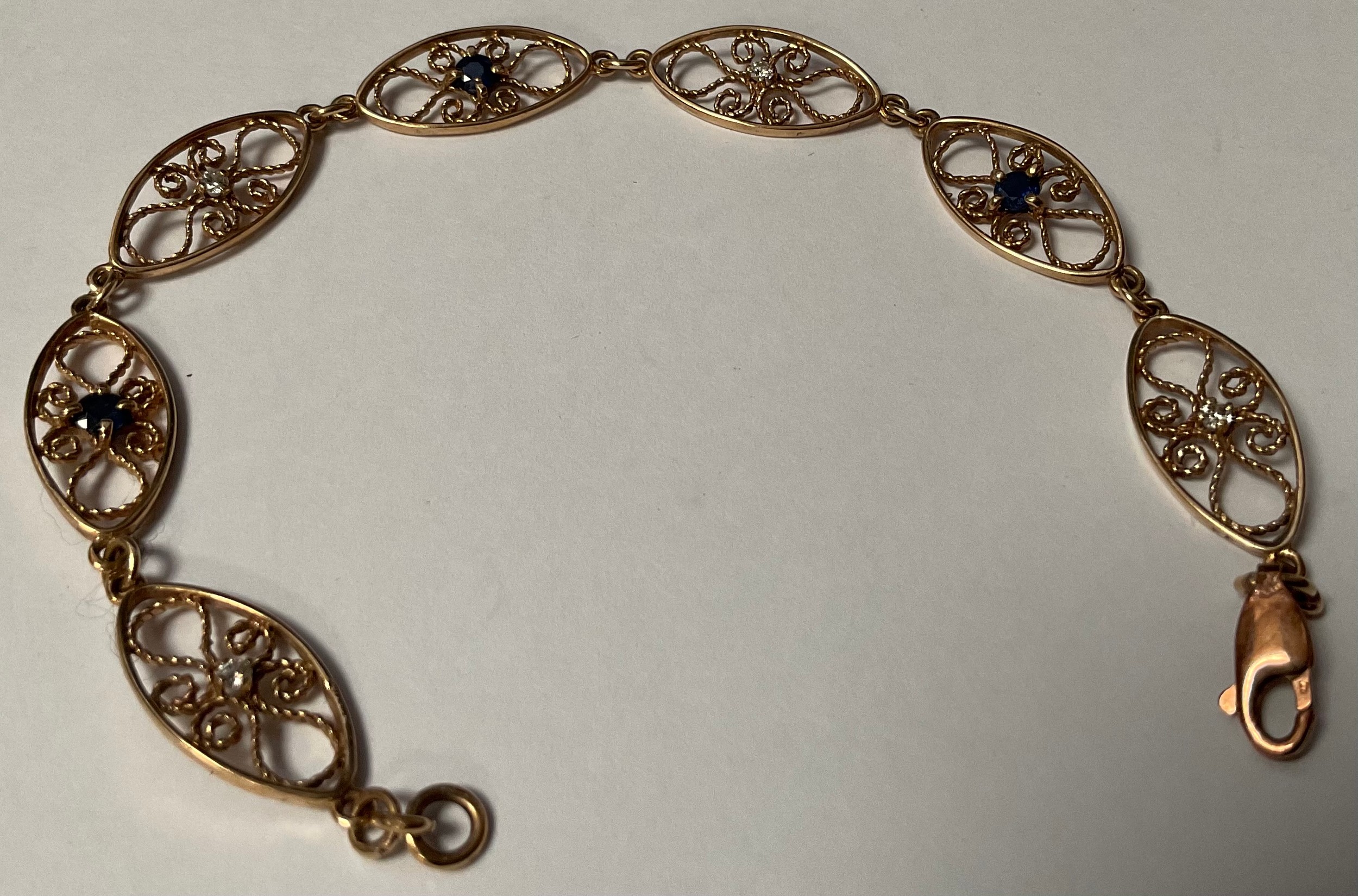 An unmarked gold openwork filigree bracelet, the seven oval links set alternately with sapphire - Image 2 of 2