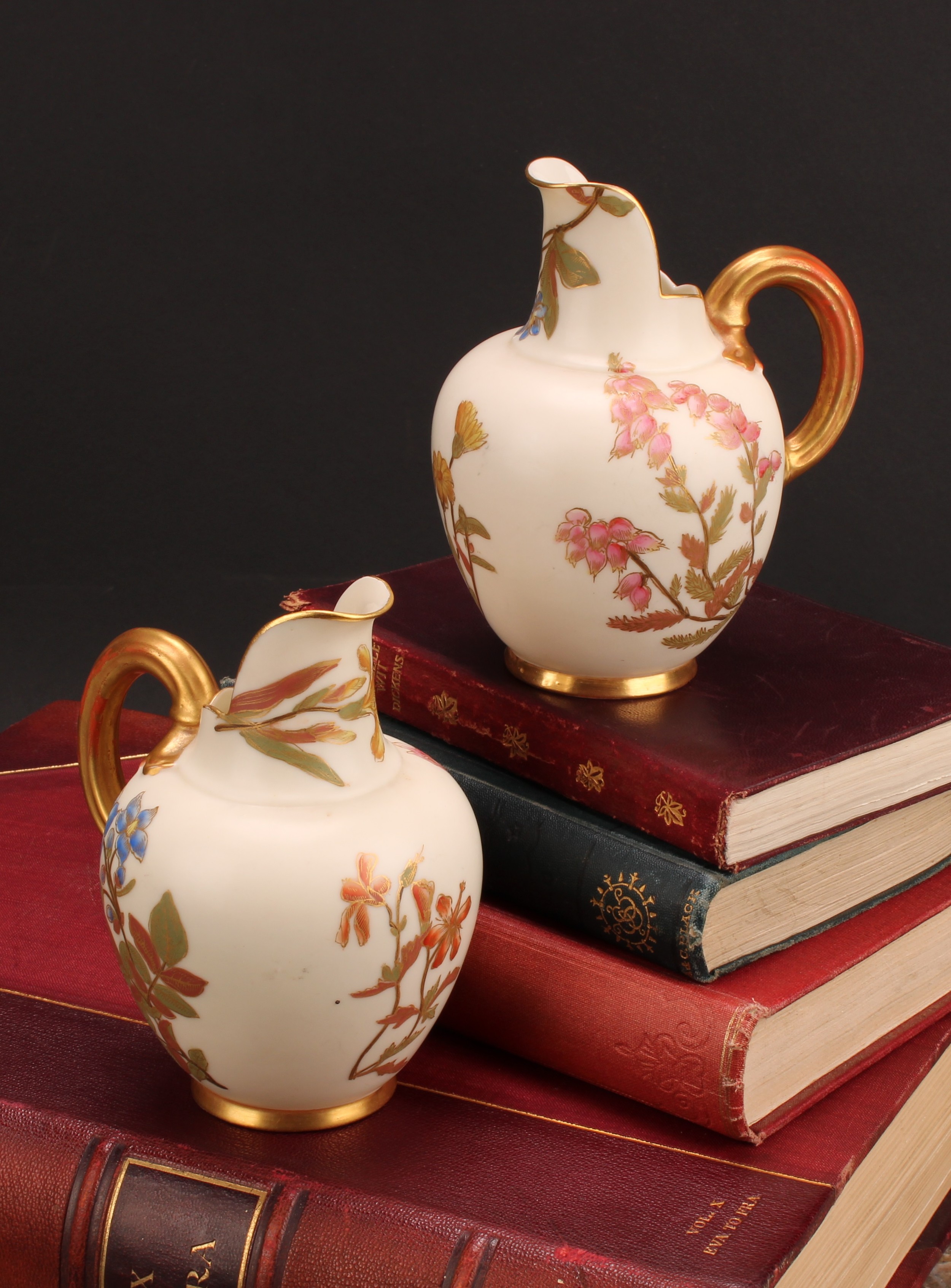 A pair Royal Worcester flat back jugs, decorated in the Aesthetic manner with floral sprays in muted