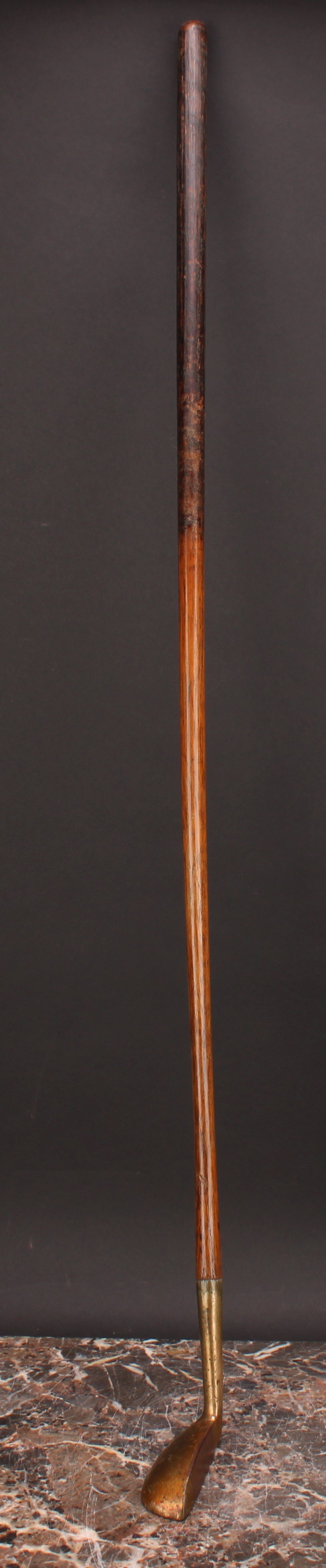 Golf Club - an early 20th century putter, lacquered brass finish, inlaid iron sole, hickory shaft,