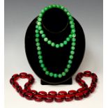 A string of green jade effect beads, approx. 80cm long; a string of faux amber beads, approx. 80cm