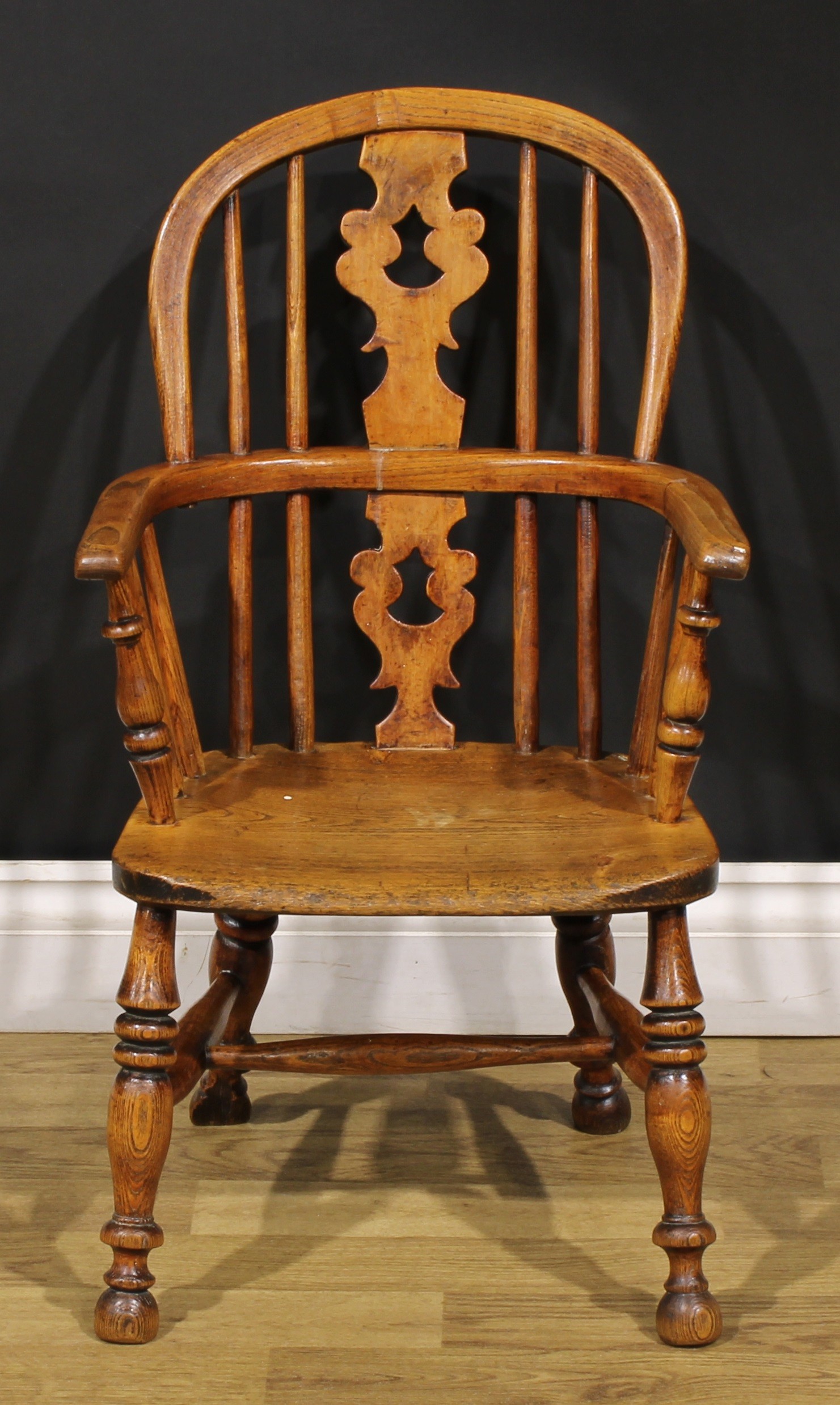 A 19th century ash and elm child’s Windsor elbow chair, pierced ‘Christmas tree’ splat, 67cm high,