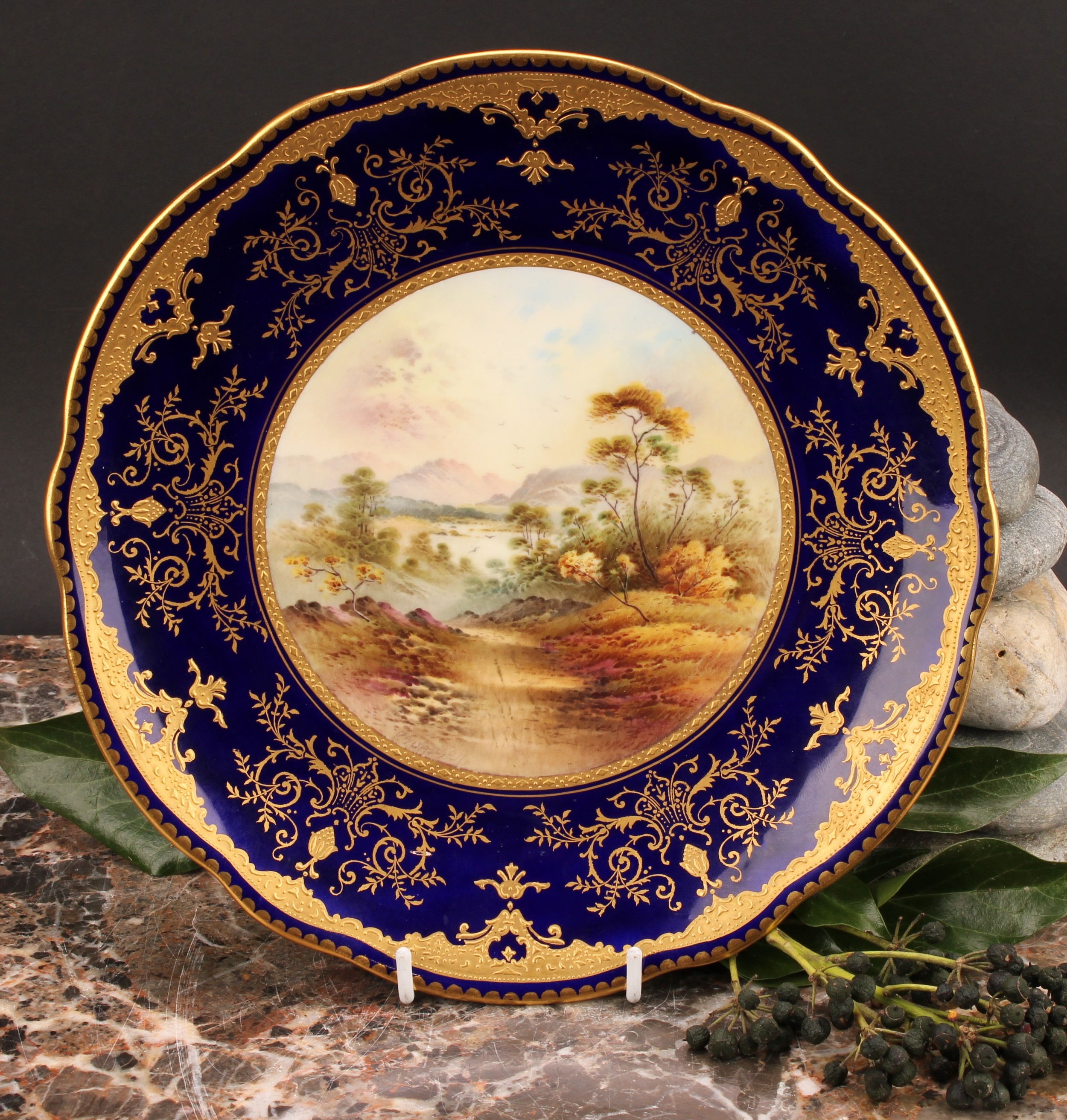 A Coalport Named View shaped circular plate, painted by P. Simpson, signed, In The Grampian Hills,