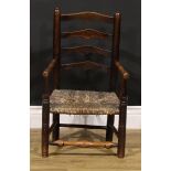 A 19th century elm child's chair, shaped ladder back, turned arms, legs and stretchers, rush seat,
