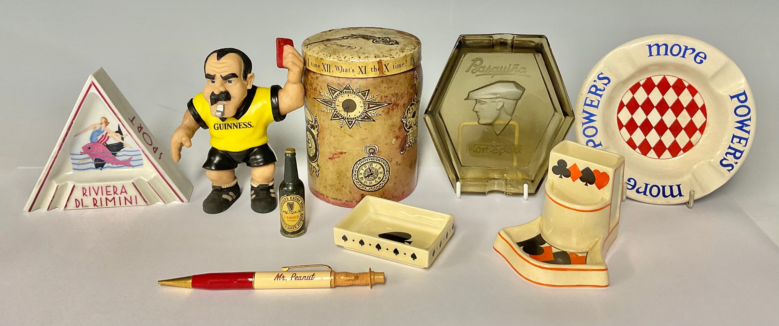 A Guinness squishy Rugby referee and miniature bottle of beer; a Cadbury's drinking chocolate tin,