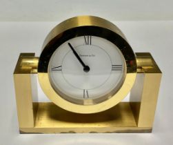 A Tiffany & Co brass clock, white circular dial with Roman numerals to quarters, rotating on a
