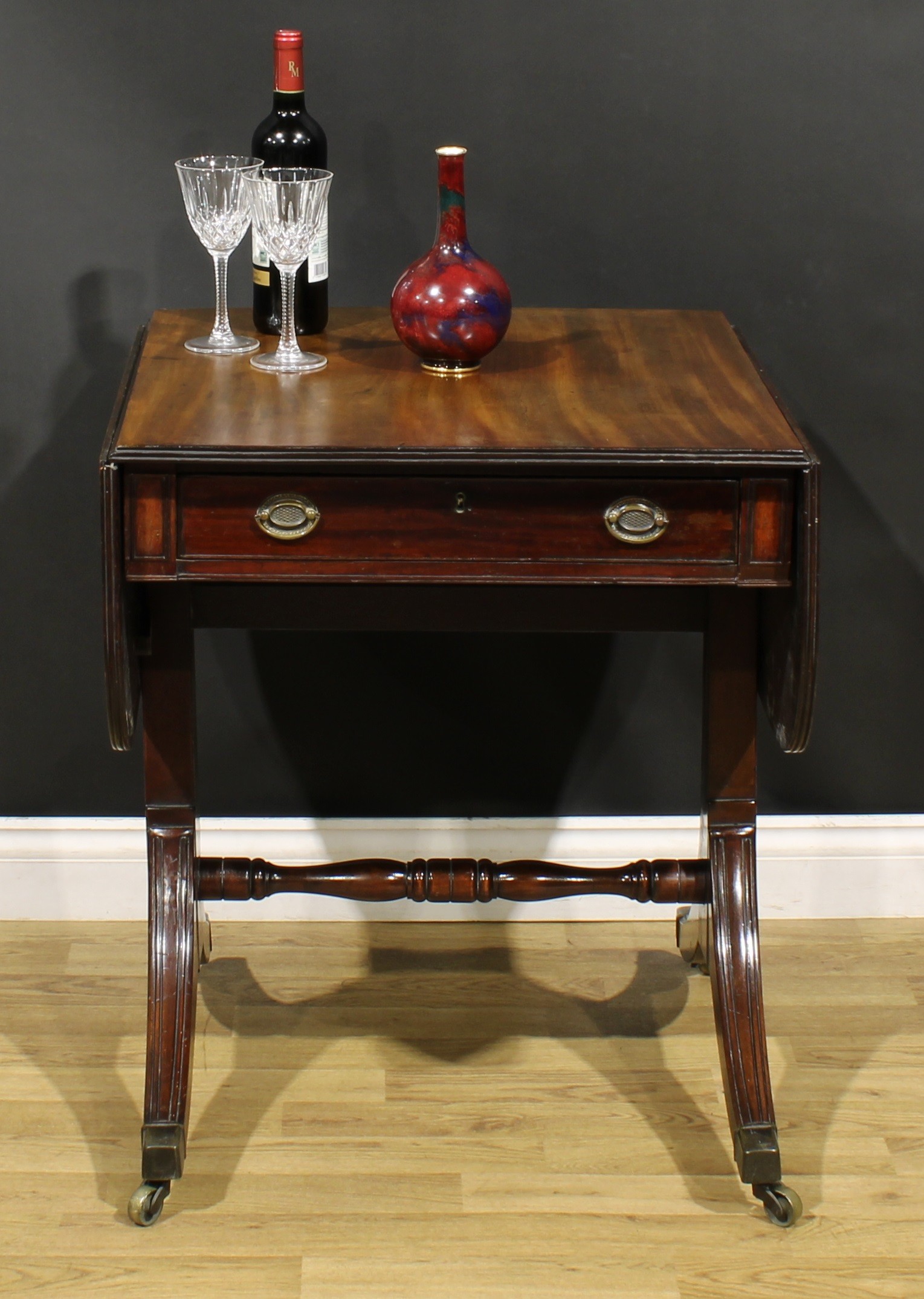 A 19th century mahogany sofa table, rounded rectangular top with fall leaves above a frieze
