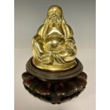 A brass seated laughing Buddha figure, 11cm, pierced circular hardwood stand