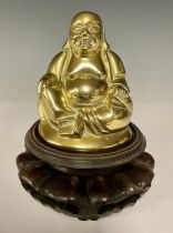 A brass seated laughing Buddha figure, 11cm, pierced circular hardwood stand