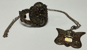 An Indian silver cuff bracelet as a fearsome mask, marked 925, 27g; a similar pendant, marked 90% on