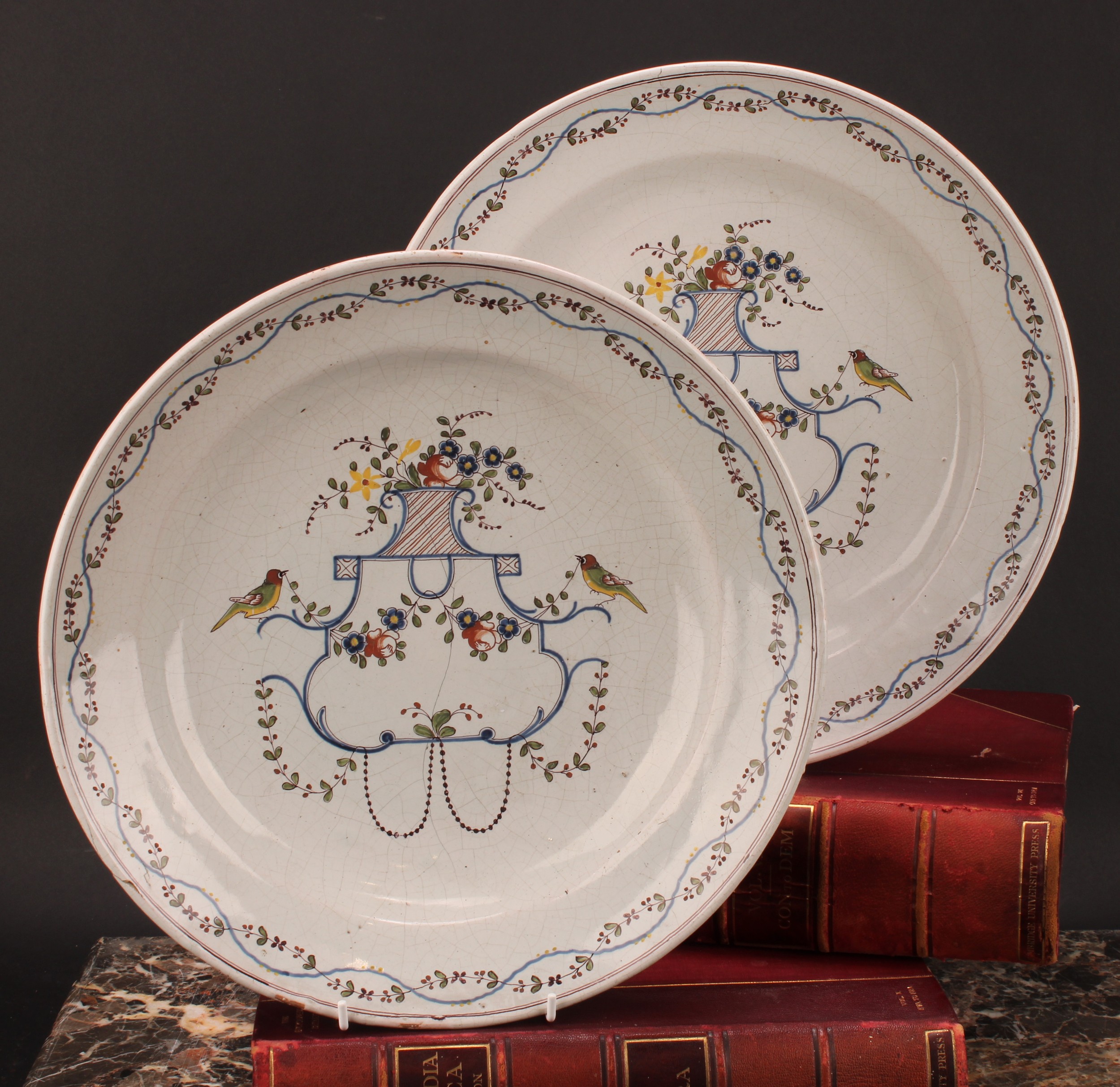 A pair of Delft chargers, painted in polychrome with birds, flowers and floral swags, 33cm diameter