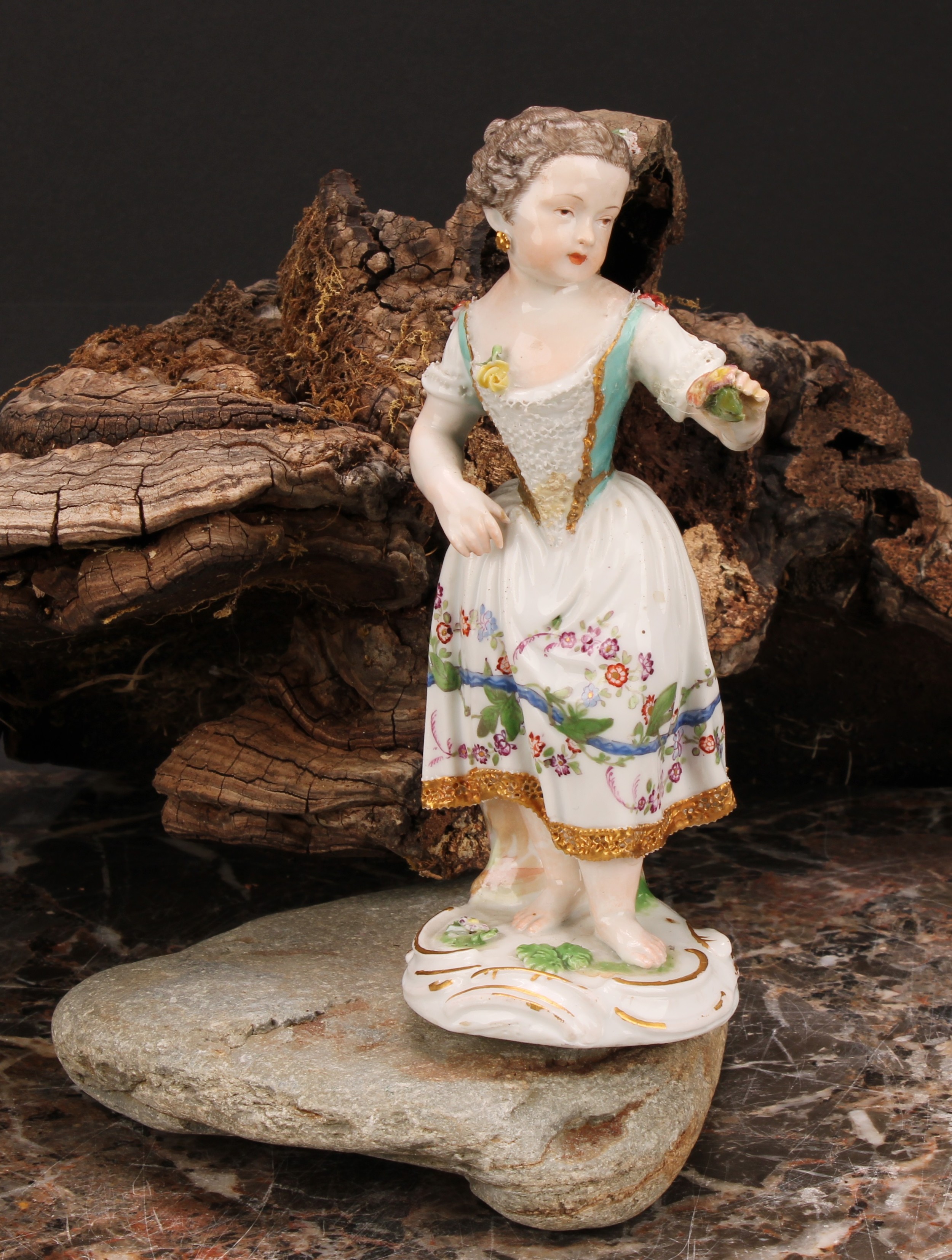 A Meissen porcelain figure, of a girl wearing a floral dress, with posies in hand, scroll base,