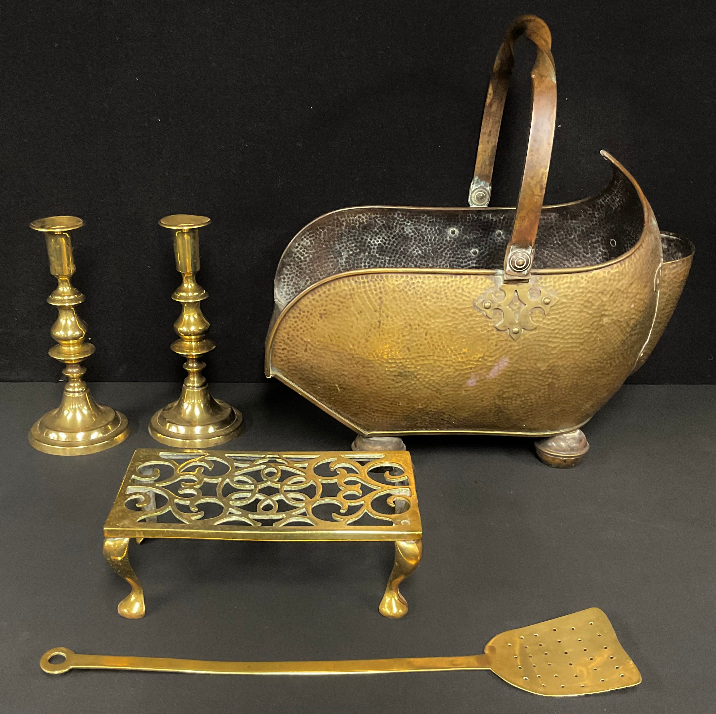 A harlequin hearth suite comprising a Victorian copper coal scuttle, a pair of brass candlesticks,