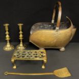 A harlequin hearth suite comprising a Victorian copper coal scuttle, a pair of brass candlesticks,