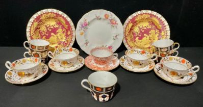 A pair of Royal Crown Derby Gold Aves pattern shaped circular plates, on a red ground, heraldic