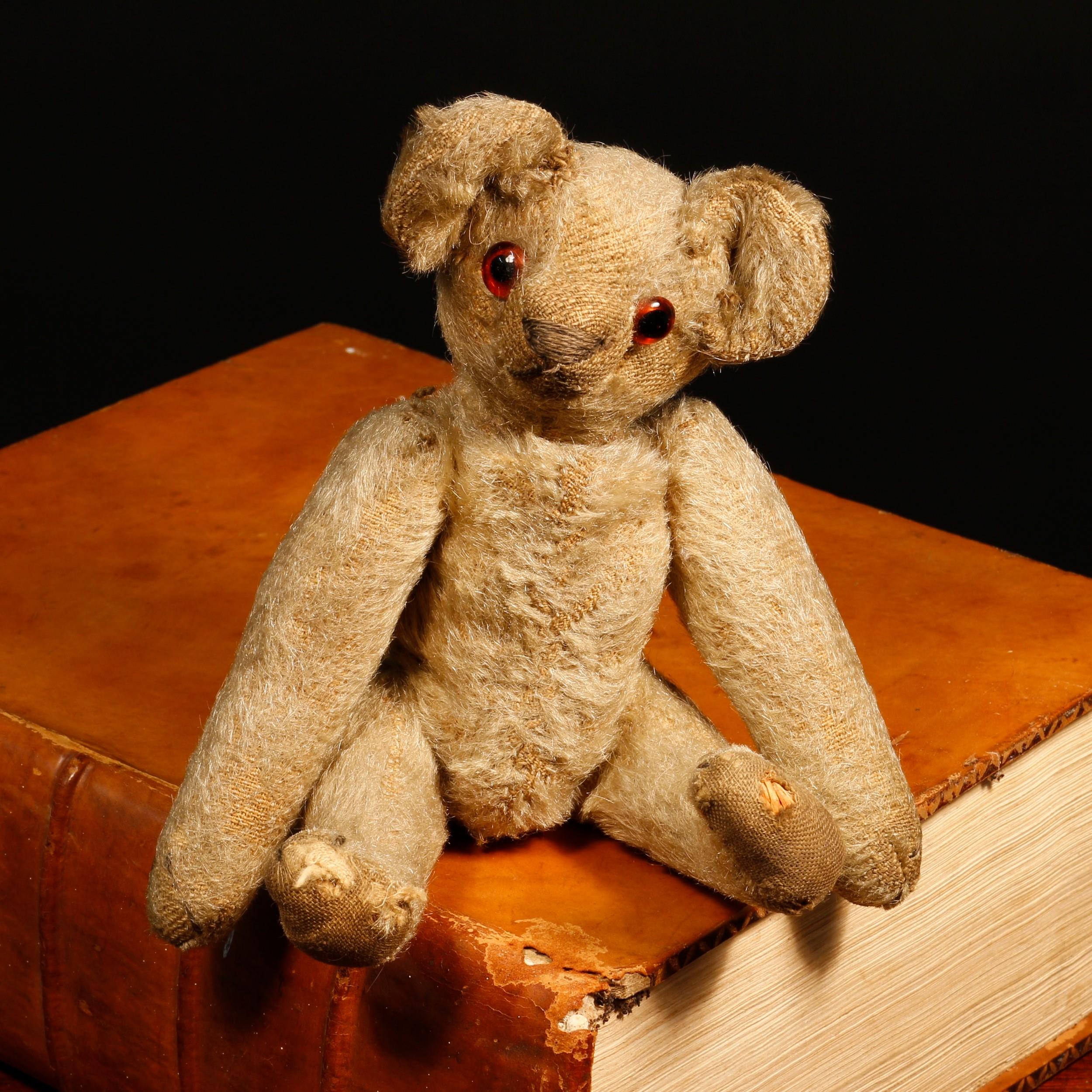 An early 20th century miniature golden mohair jointed teddy bear, amber and black glass eyes,