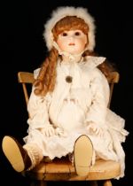 A reproduction bisque head doll, the bisque head inset with fixed brown glass eyes, painted features