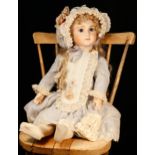 A reproduction bisque head doll, the bisque head inset with fixed blue glass eyes, painted