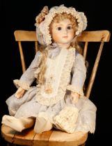 A reproduction bisque head doll, the bisque head inset with fixed blue glass eyes, painted