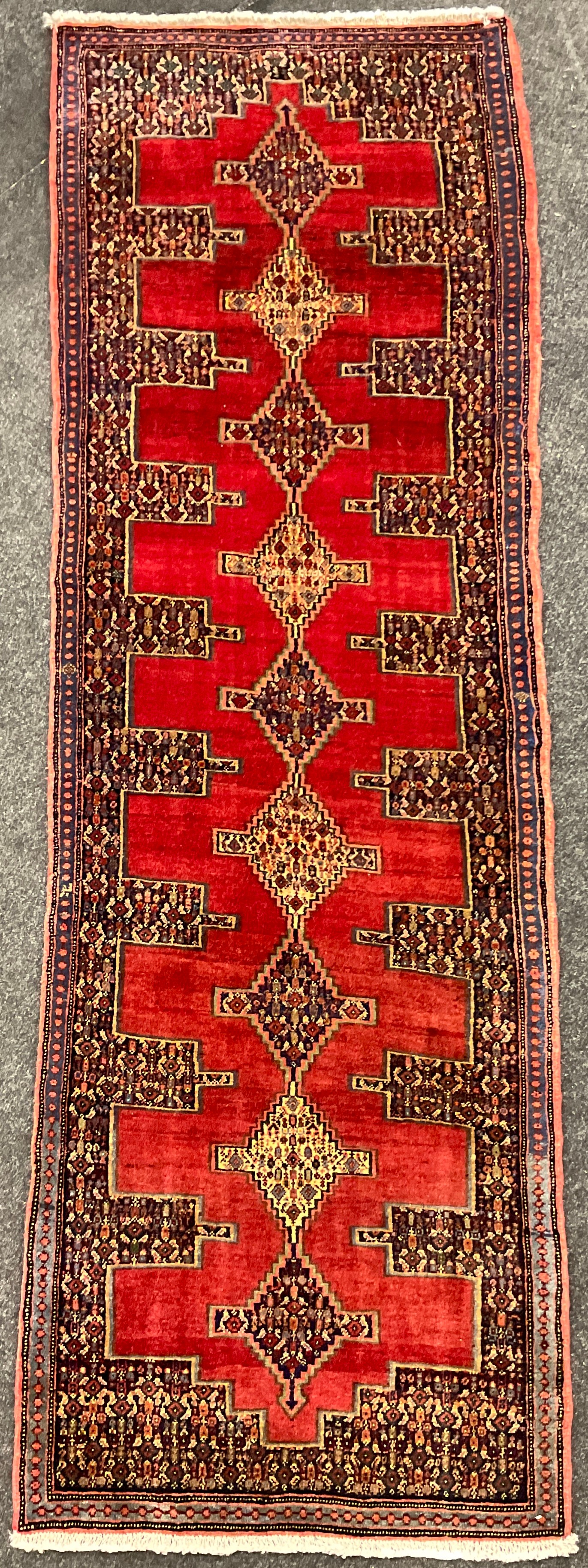 A North-west Persian Senneh Runner carpet, central row of nine diamond-shaped medallions, within a