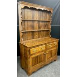 An oak dresser, by Andrew Sharpe furniture, of Matlock, Derbyshire, having a three tier plate-rack