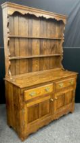 An oak dresser, by Andrew Sharpe furniture, of Matlock, Derbyshire, having a three tier plate-rack