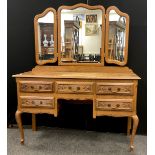 A French Provincial style oak dressing table, serpentine shaped triple mirror, above a base with