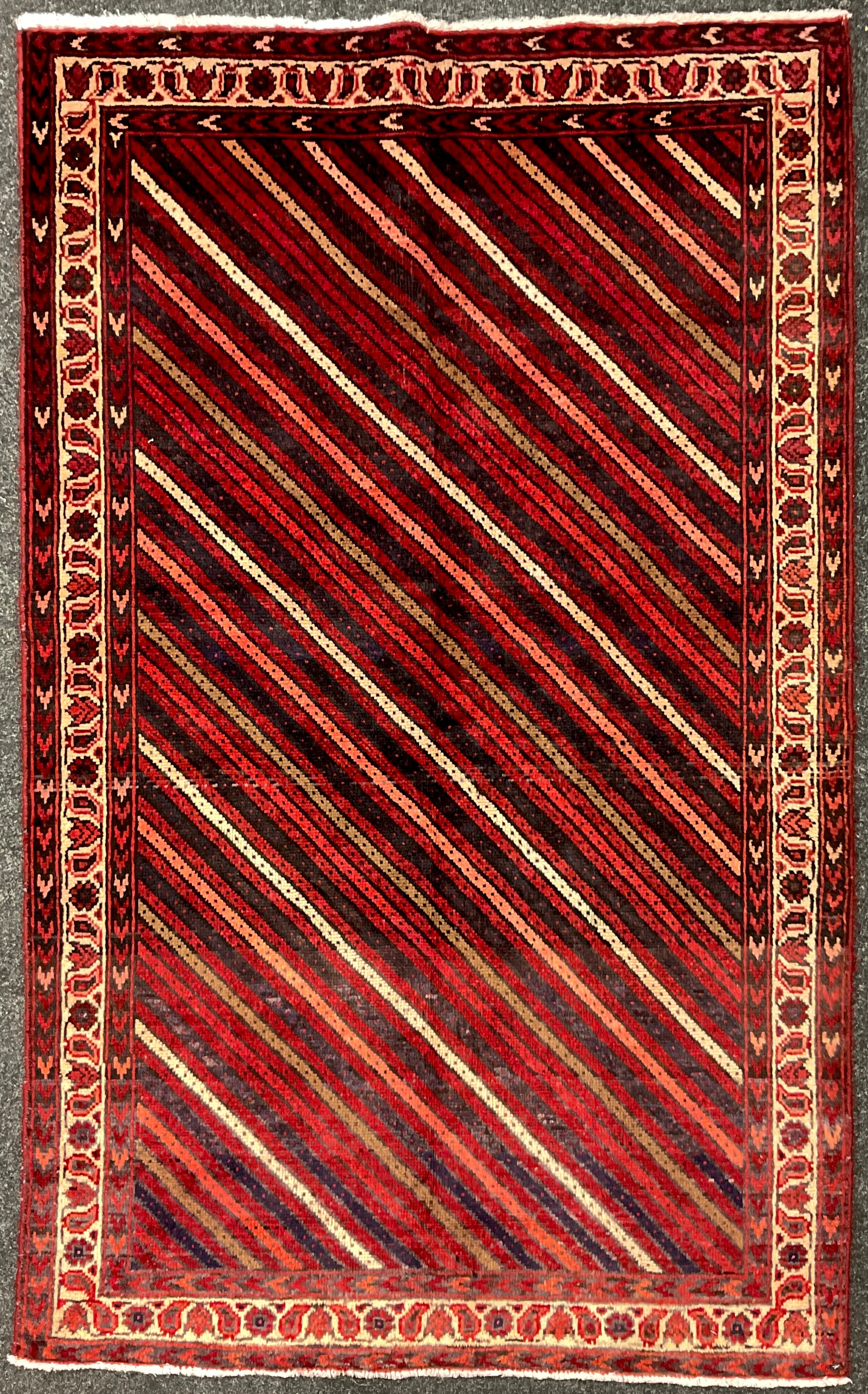 A South-west Persian Lori rug / carpet, hand-knotted, in tones of red, pink, deep indigo, and cream,