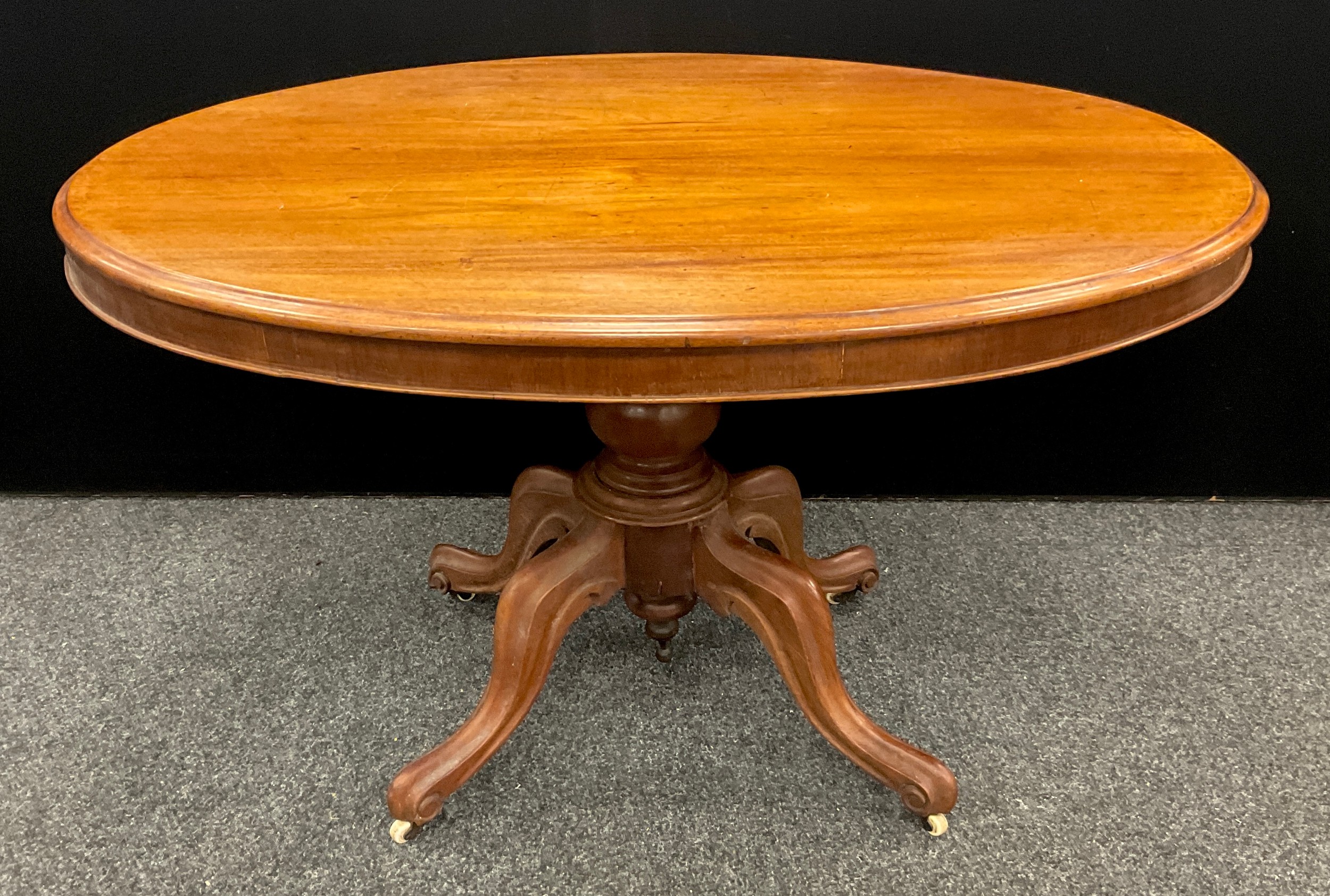 A Late Victorian mahogany Loo Table, oval top tilt-top, turned pedestal base with four carved,