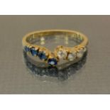 A diamond and sapphire dress ring, off set crest with slightly graduated four stone set shoulders,