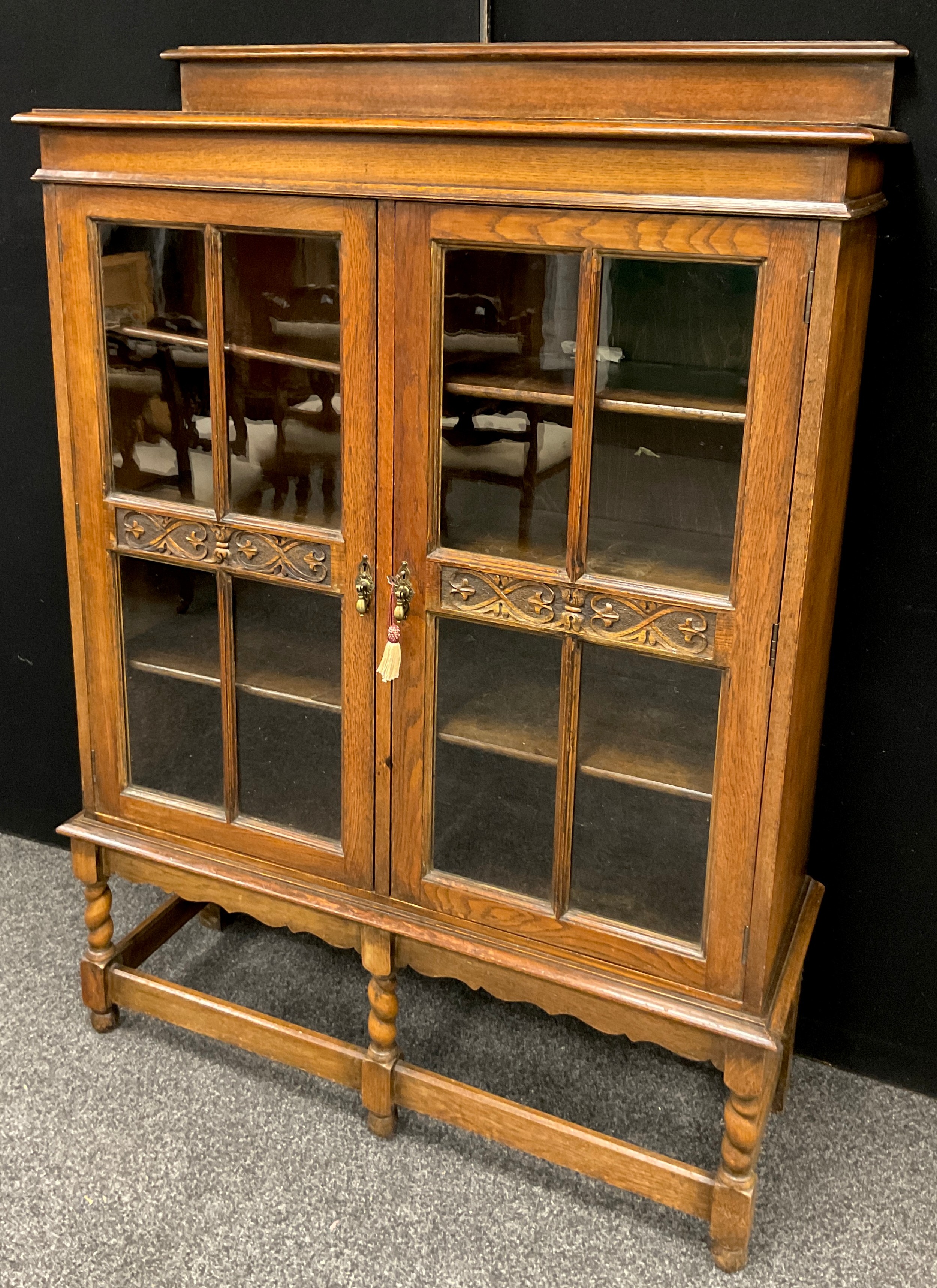 An Arts and Crafts style oak cabinet, 149.5cm high x 106.5cm wide x 34.5cm deep, early 20th century.
