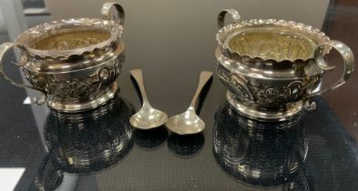 A cased pair of Edwardian silver twin handled table salts, clear glass liners, Birmingham 1904,