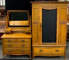 An early 20th century Arts and Crafts style oak wardrobe and dressing table, with Art Nouveau carved