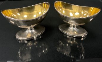 A pair of George III silver boat shaped table salts, gilt interiors, ridged lip, the side engraved